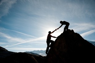 Picture of a man helping another man to reach the top of the mounting representing client website and document content writing, SEO, editing services