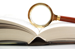 Picture of open book and magnifying glass for manuscript content analysis and revision
